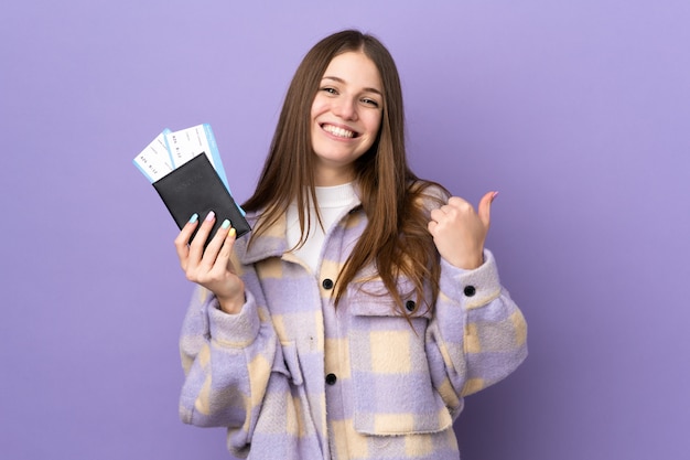 Young caucasian woman on purple in vacation holding a passport and plane with thumb up