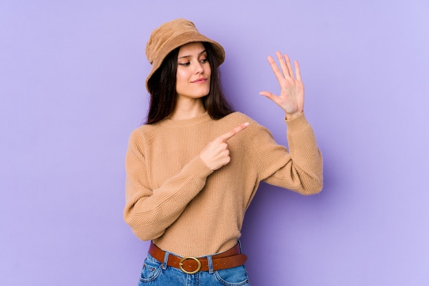 Young caucasian woman on purple wall smiling cheerful showing number five with fingers.