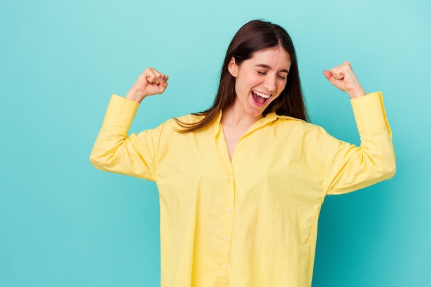 Young caucasian woman raising fist after a victory, winner concept.