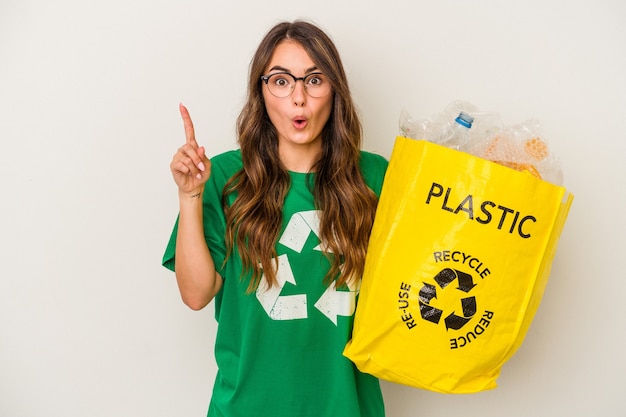 Young caucasian woman recycling a full of plastic isolated on white background  having some great idea, concept of creativity.