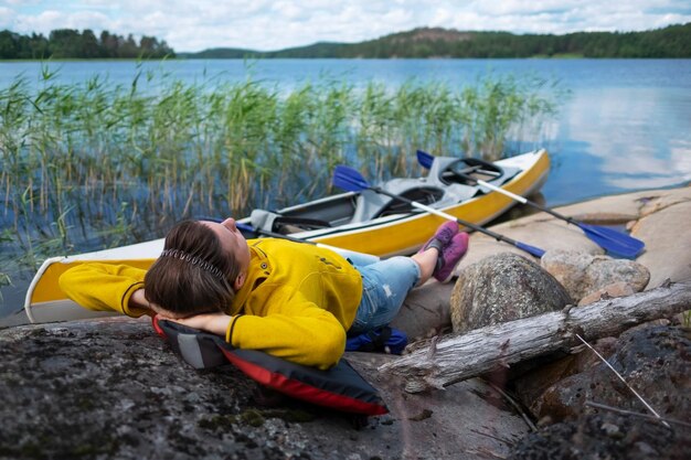 Foto giovane donna caucasica che riposa sulla riva del fiume dopo il kayak