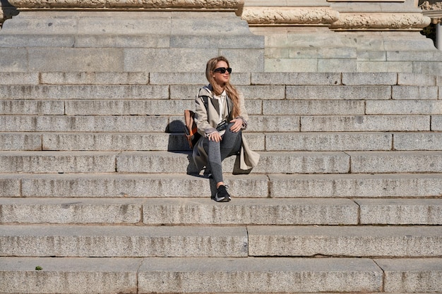 Photo young caucasian woman resting on stairs during travel