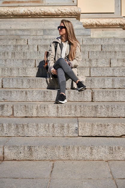 Young caucasian woman resting on stairs during travel