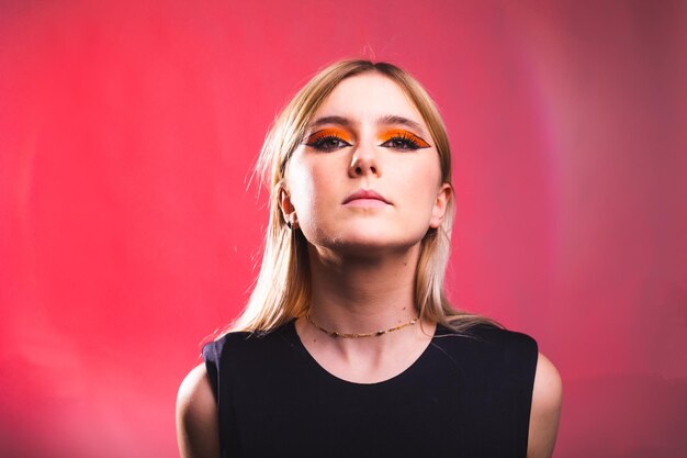 Volto serio di giovane donna caucasica in uno studio fotografico con uno sfondo rosso.