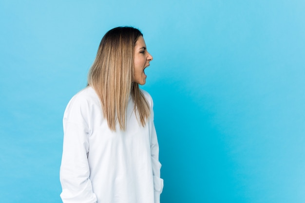 Young caucasian woman shouting towards a copy space