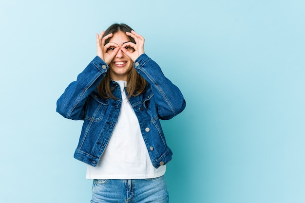 Young caucasian woman showing okay sign over eyes