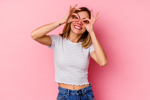 Young caucasian woman  showing okay sign over eyes