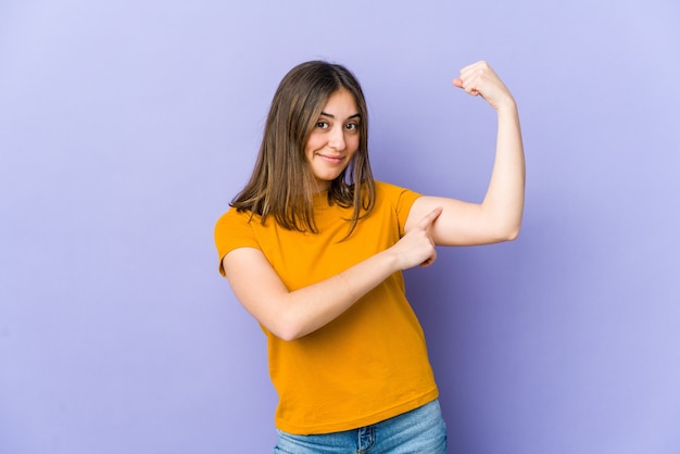 Young caucasian woman showing strength gesture with arms, symbol of feminine power