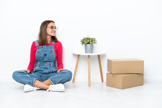 Young caucasian woman sitting on the floor among boxes in lateral position