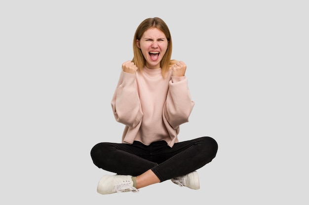 Young caucasian woman sitting on the floor cutout isolated