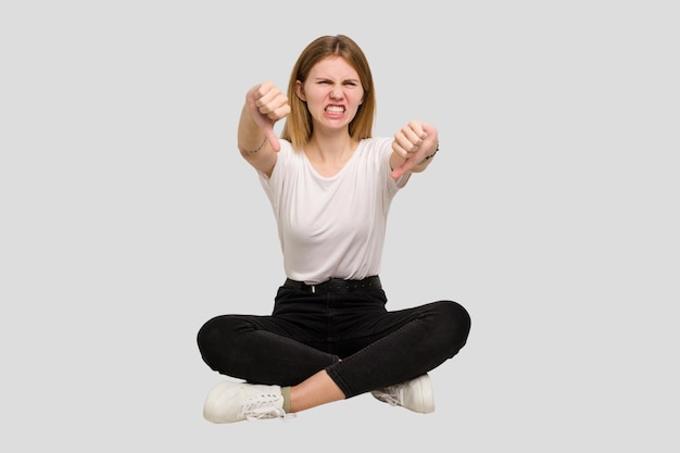 Young caucasian woman sitting on the floor cutout isolated