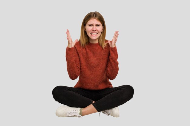 Young caucasian woman sitting on the floor cutout isolated