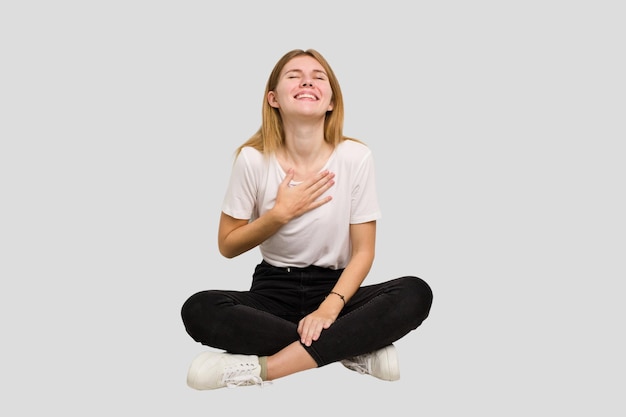 Young caucasian woman sitting on the floor cutout isolated