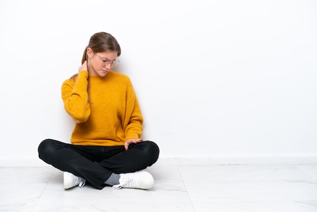 Young caucasian woman sitting on the floor isolated on white background with neckache