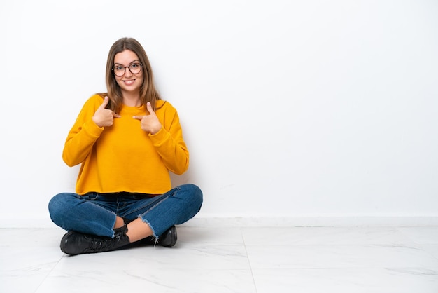 Young caucasian woman sitting on the floor isolated on white background with surprise facial expression