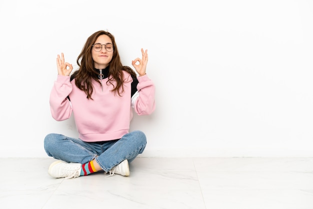 Photo young caucasian woman sitting on the floor isolated on white background in zen pose