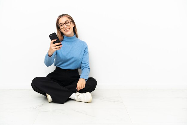 Giovane donna caucasica seduta sul pavimento facendo un selfie