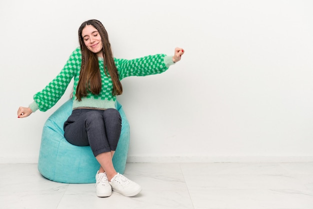 Young caucasian woman sitting on a puff isolated on white background