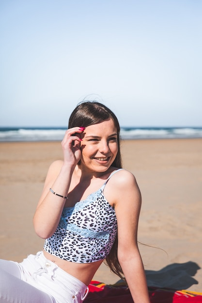 Young caucasian woman sitting on a towel at the beach