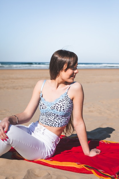 Young caucasian woman sitting on a towel at the beach