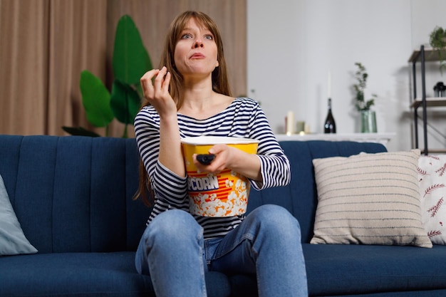 Young caucasian woman spending her leisure at home watching TV