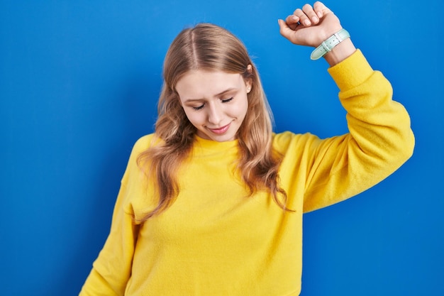 Young caucasian woman standing over blue background dancing happy and cheerful smiling moving casual and confident listening to music