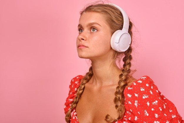 Young caucasian woman teen in headphones looks up listening to audio lecture