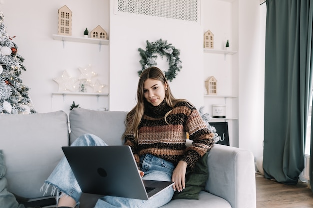 Young caucasian woman using laptop computer in holidays at home on the sofa.