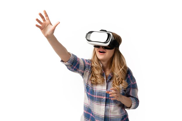 Young caucasian woman using VR-headset devices, gadgets isolated on white  wall. Concept of modern technologies, gadgets, tech, emotions, ad. Copyspace. Gaming, meeting online education.