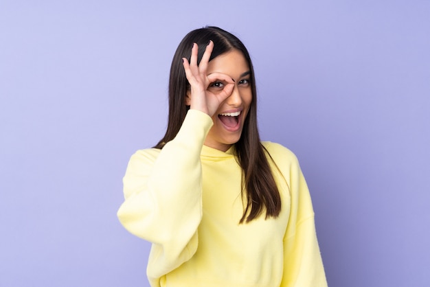 Young caucasian woman over wall showing ok sign with fingers