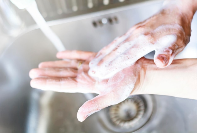 Foto una giovane donna caucasica si lava le mani con sapone per l'igiene personale e la prevenzione dei virus