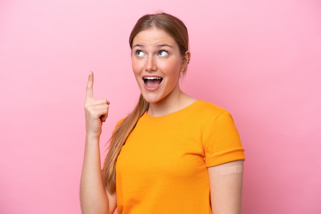 Young caucasian woman wearing band aid isolated on pink background intending to realizes the solution while lifting a finger up