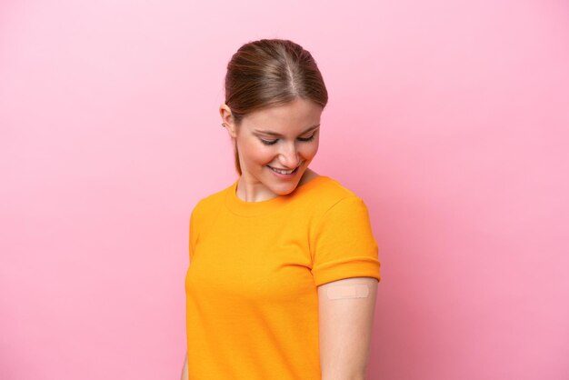 Young caucasian woman wearing band aid isolated on pink background with happy expression