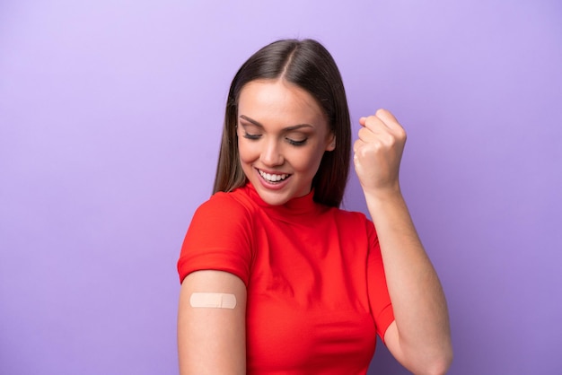 Young caucasian woman wearing band aid isolated on purple background celebrating a victory