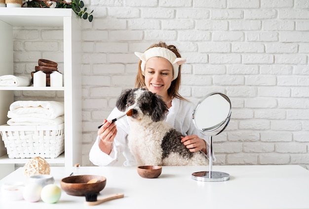 Young caucasian woman wearing bathrobes doing spa procedures with her dog