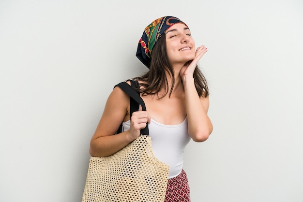 Young caucasian woman wearing a beach bag isolated on white background