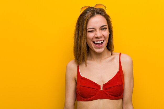 Photo young caucasian woman wearing bikini and sunglasses winking, funny, friendly and carefree.