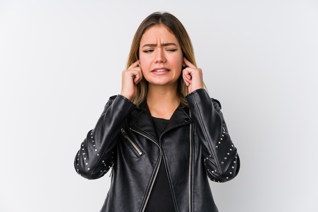 Young caucasian woman wearing a black leather jacket covering ears with hands.