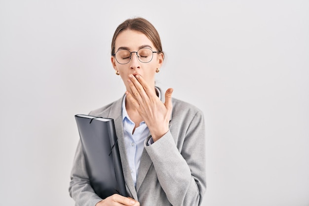 Young caucasian woman wearing business clothes and glasses bored yawning tired covering mouth with hand restless and sleepiness