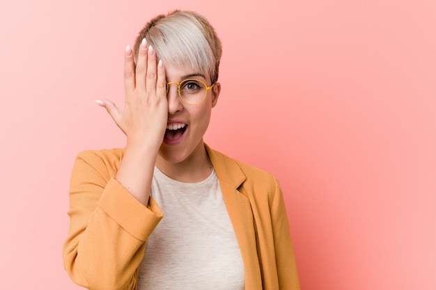 Young caucasian woman wearing a casual business clothes having fun covering half of face with palm.