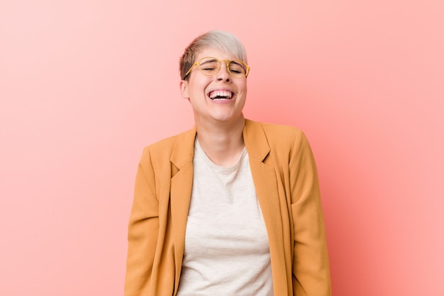 Photo young caucasian woman wearing a casual business clothes laughs and closes eyes, feels relaxed and happy.