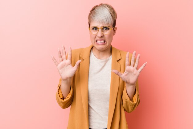 Young caucasian woman wearing a casual business clothes rejecting someone showing a gesture of disgust.