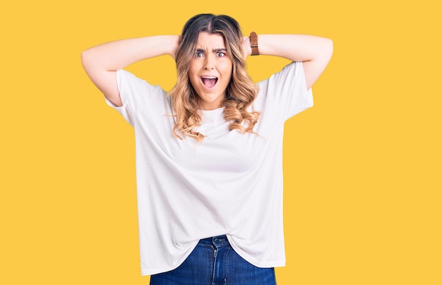 Young caucasian woman wearing casual clothes crazy and scared with hands on head, afraid and surprised of shock with open mouth