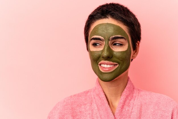 Young caucasian woman wearing a face mask isolated on pink background