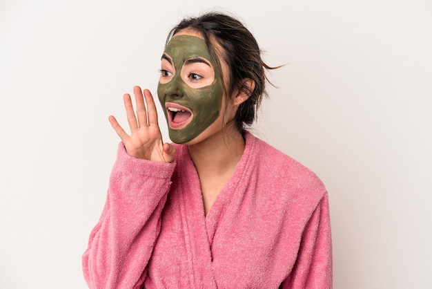 Young caucasian woman wearing a facial mask isolated on white background shouting and holding palm near opened mouth