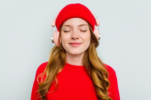 Young caucasian woman wearing headphones isolated on blue background