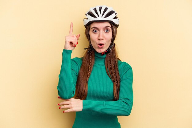 Young caucasian woman wearing a helmet bike isolated on yellow
background having some great idea concept of creativity