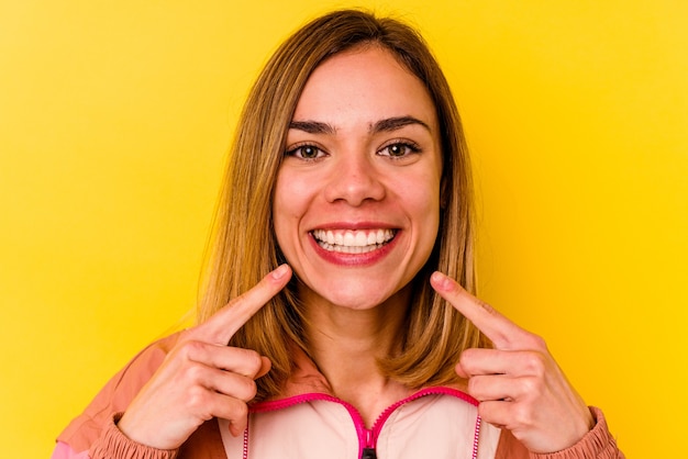 黄色の壁に分離された目に見えない歯列矯正を身に着けている若い白人女性
