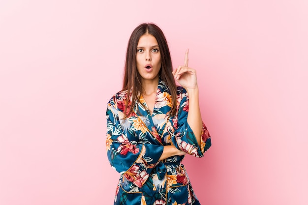 Young caucasian woman wearing a kimono pajama having some great idea, concept of creativity.