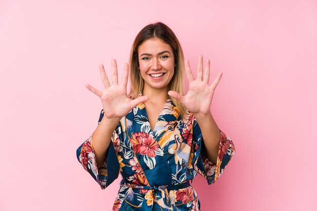 Young caucasian woman wearing pajamas showing number ten with hands.